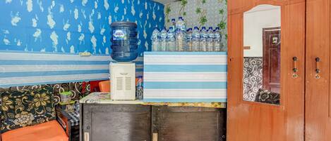 A room with a blue and white patterned wall, a water dispenser, and a cabinet with a sign.