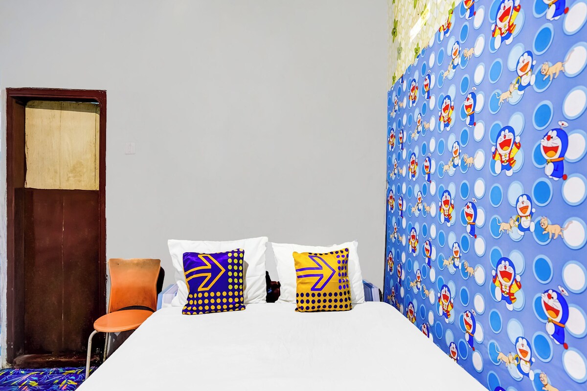 Een kamer met een bed, twee kussens, een stoel, een deur en een muur met een striptekeningpatroon.