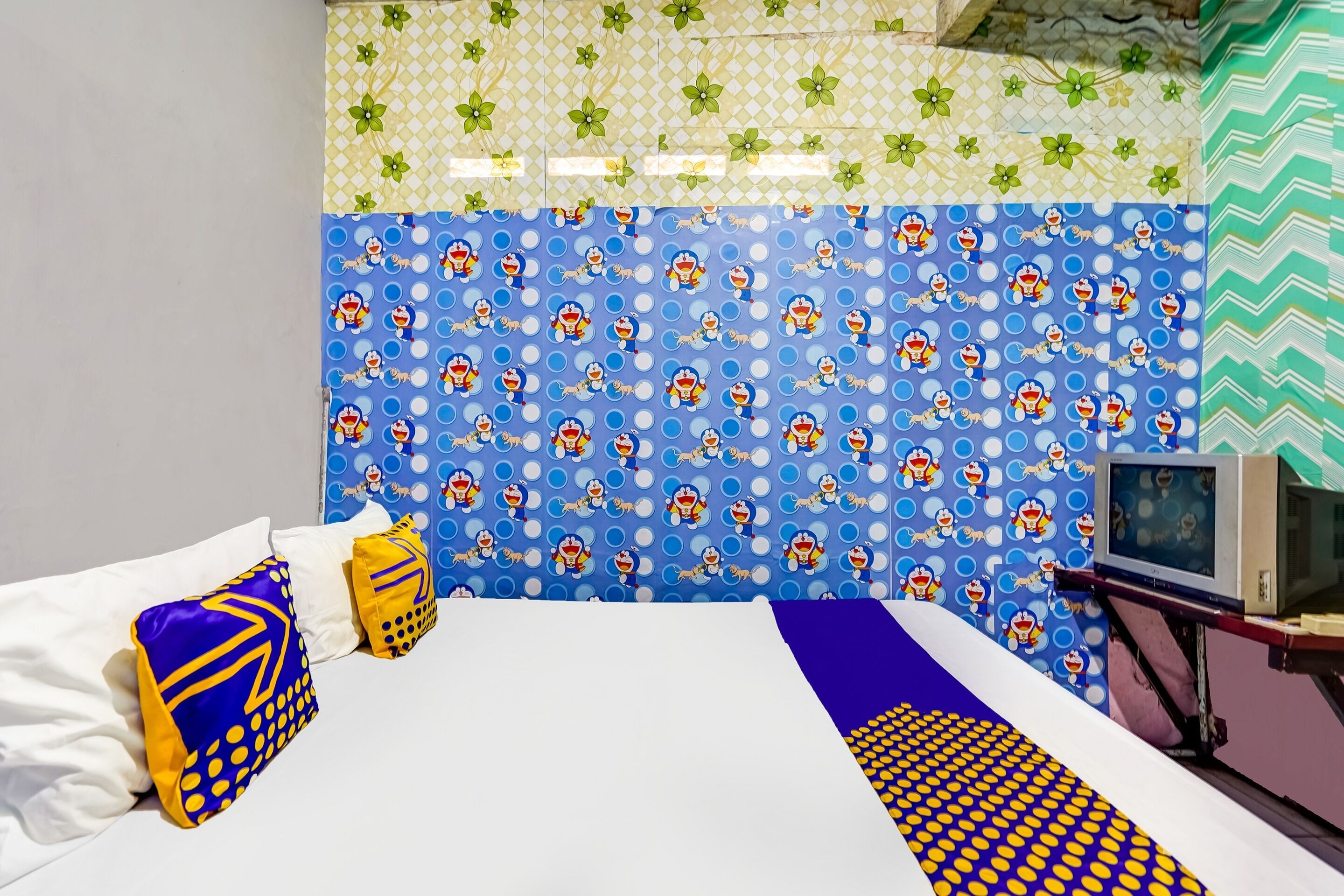 Una habitación de hotel con cama, almohadas, televisor y pared con diseño.