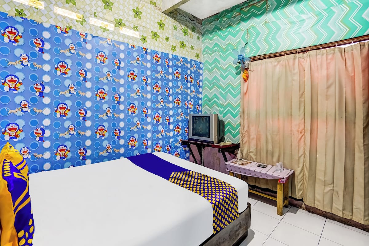 Una stanza con un letto, una televisione su un mobile in legno e pareti decorate.