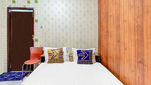 A bed with white bedding, two pillows with geometric patterns, a red chair, and a patterned wall. - OYO Life 91060 Villa Wijaya Homestay (Prigen)