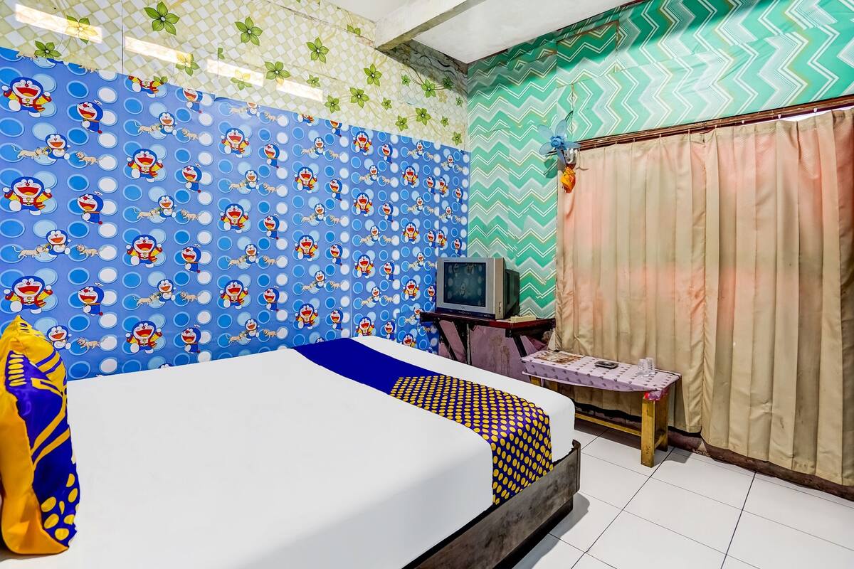 Una stanza con un letto, una televisione su un mobile e un tavolo con una tovaglia decorata.
