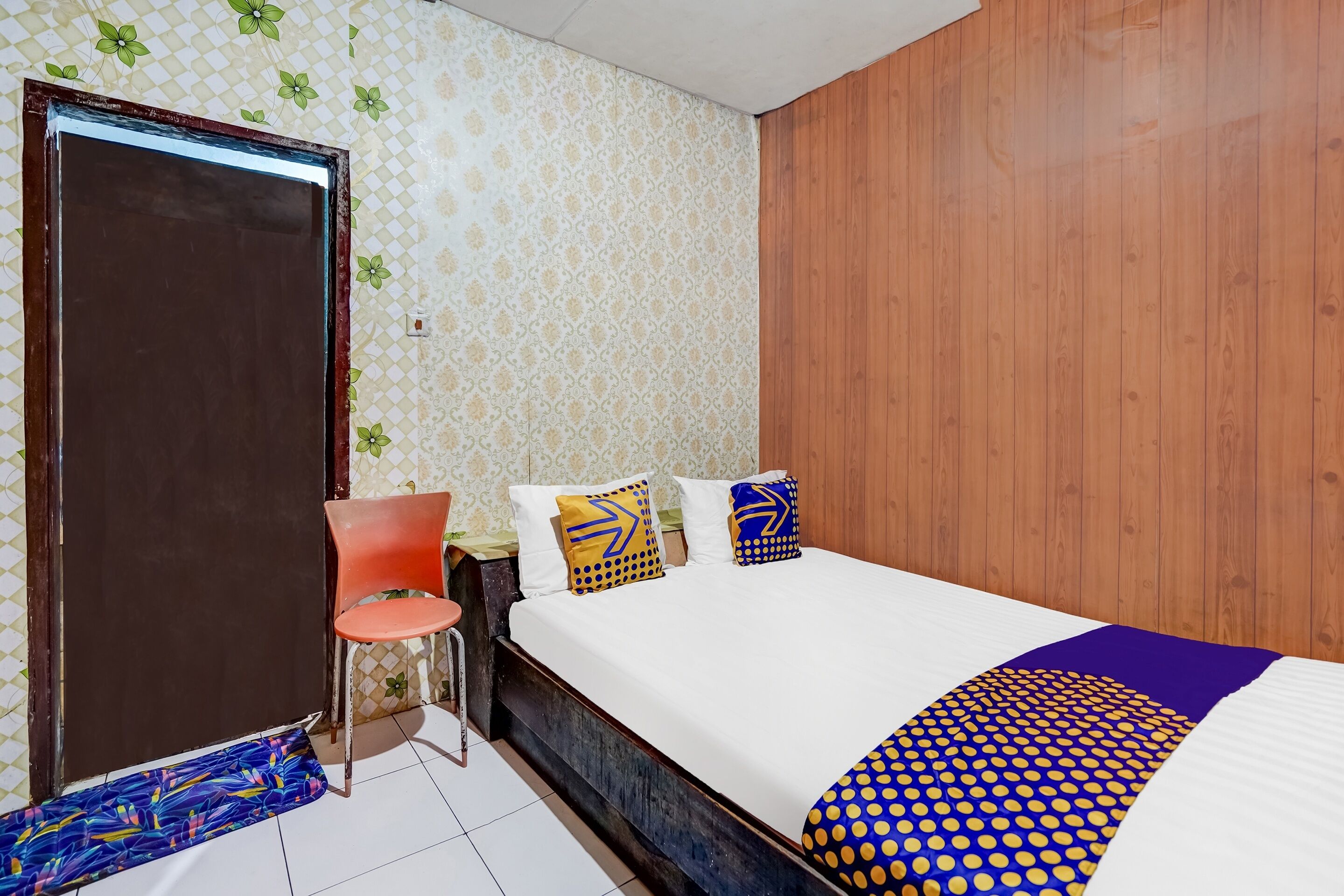 A bedroom with a bed, a chair, a desk, and a wardrobe.