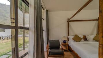 A four-poster bed with a wooden frame, a small wooden nightstand with a lamp, and a chair.
