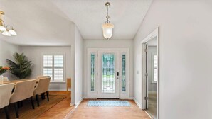A dining area with a table and chairs, a wooden floor, a ceiling light fixture, and a door with a glass panel. - *True Blue Pool Oasis* ping-pong, wi-fi, tv (Jacksonville)
