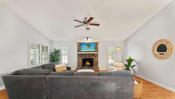 A living room with a sectional sofa, a fireplace, a ceiling fan, and a large window. - *True Blue Pool Oasis* ping-pong, wi-fi, tv (Jacksonville)
