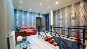 A modern living room with a red sofa, a glass coffee table, and a staircase with a metal railing. - chveni sakhli (Tbilisi)