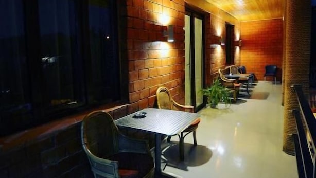 A wooden interior with a long corridor, tables, chairs, and a brick wall. - chveni sakhli (Tbilisi)