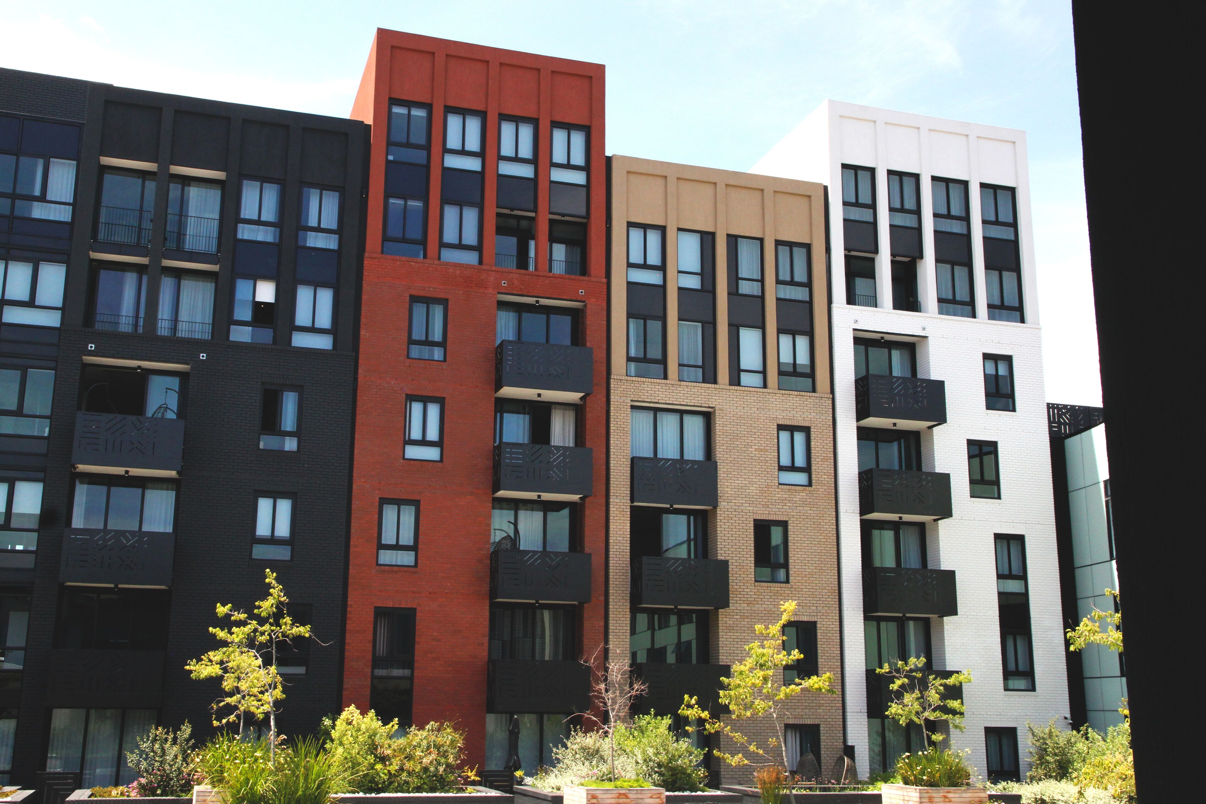 Une rangée d’immeubles modernes à plusieurs étages, dotés de balcons, qui semblent être des logements ou des bureaux, avec un ciel dégagé au-dessus.