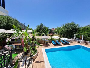 A swimming pool with lounge chairs, a barbecue area, and a view of the surrounding landscape. - ölüdeniz moonstar (Oludeniz)