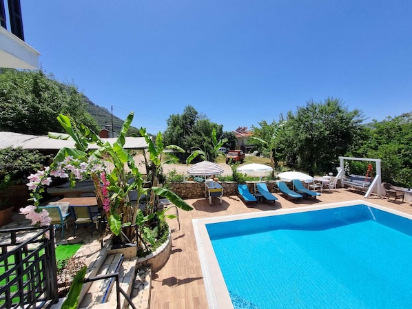 Una piscina con sillas de descanso, una zona de barbacoa y vistas del paisaje circundante.