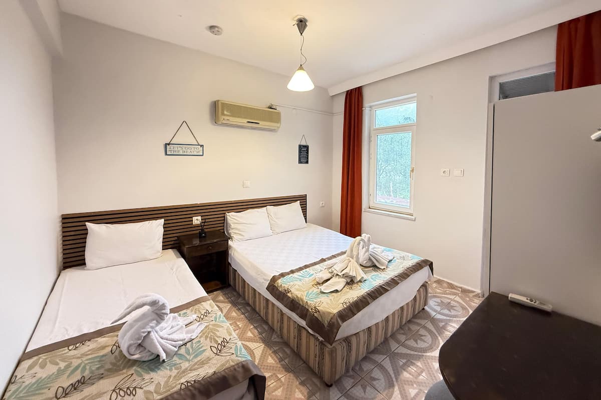 A hotel room with two beds, a window with curtains, an air conditioning unit, and a sign on the wall.
