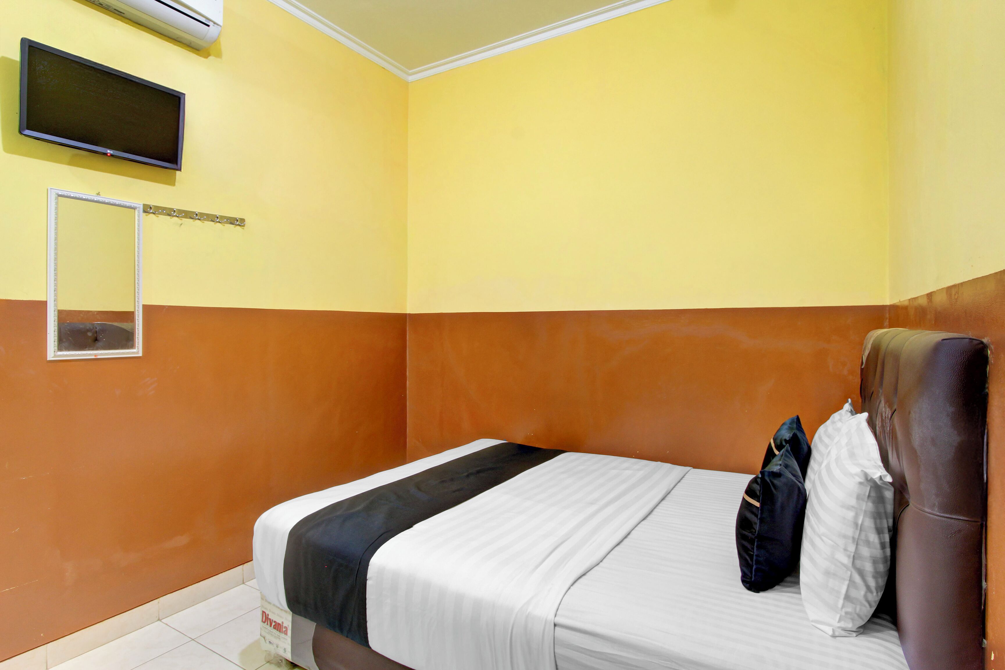 Habitación de hotel con cama, televisor montado en la pared y espejo.