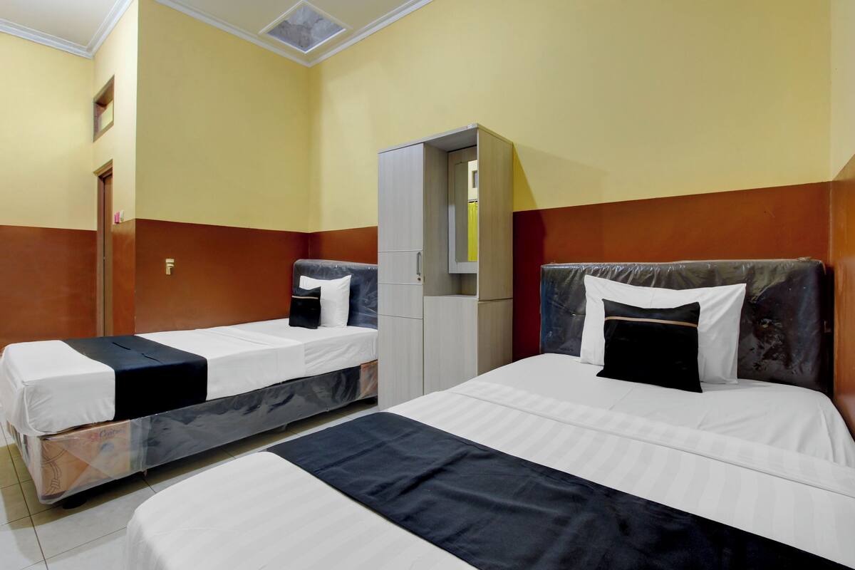 A hotel room with two beds, a wardrobe, and a mirror.