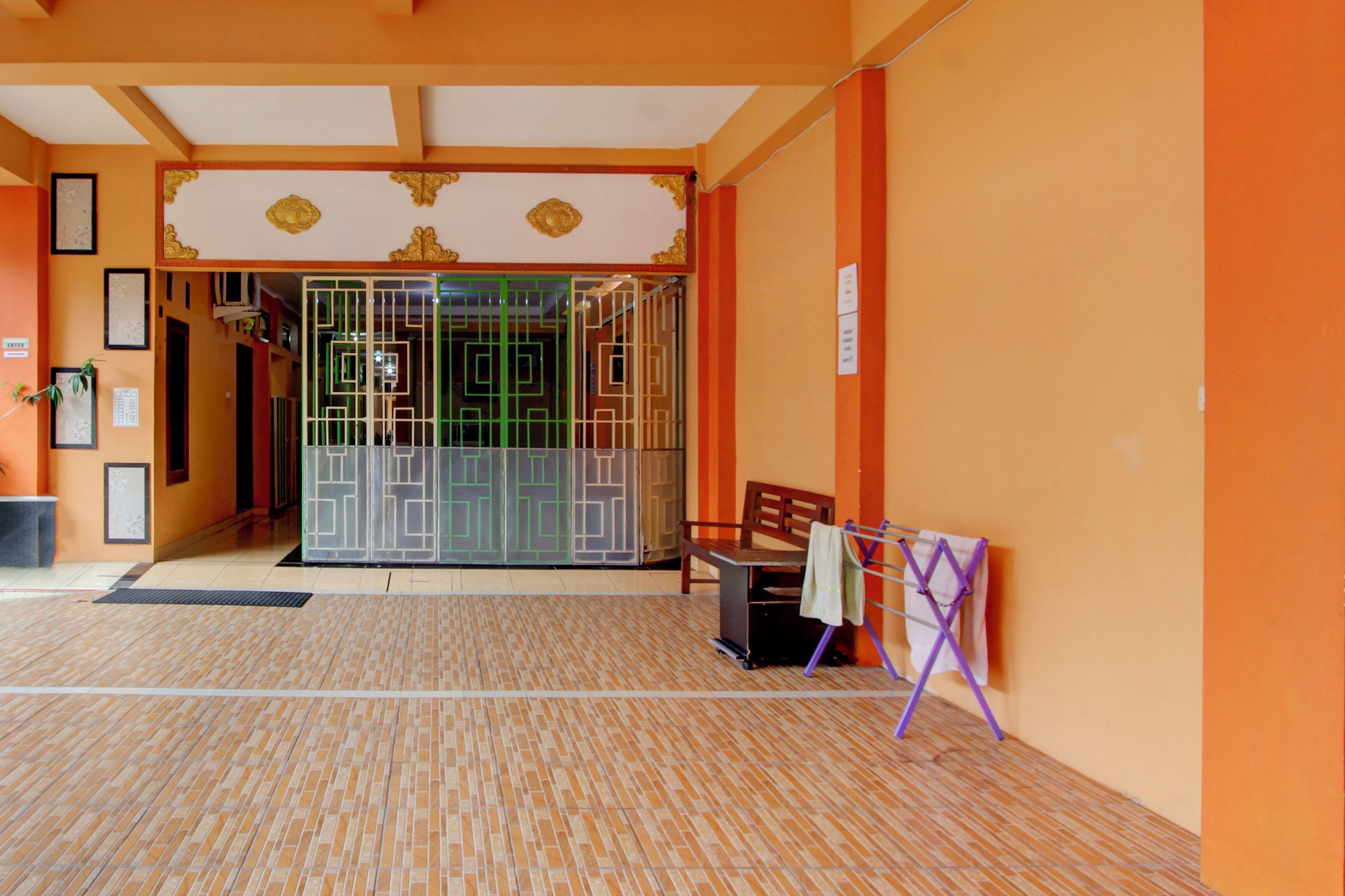 A hotel lobby with a tiled floor, a bench, a chair, and a door with a decorative frame.