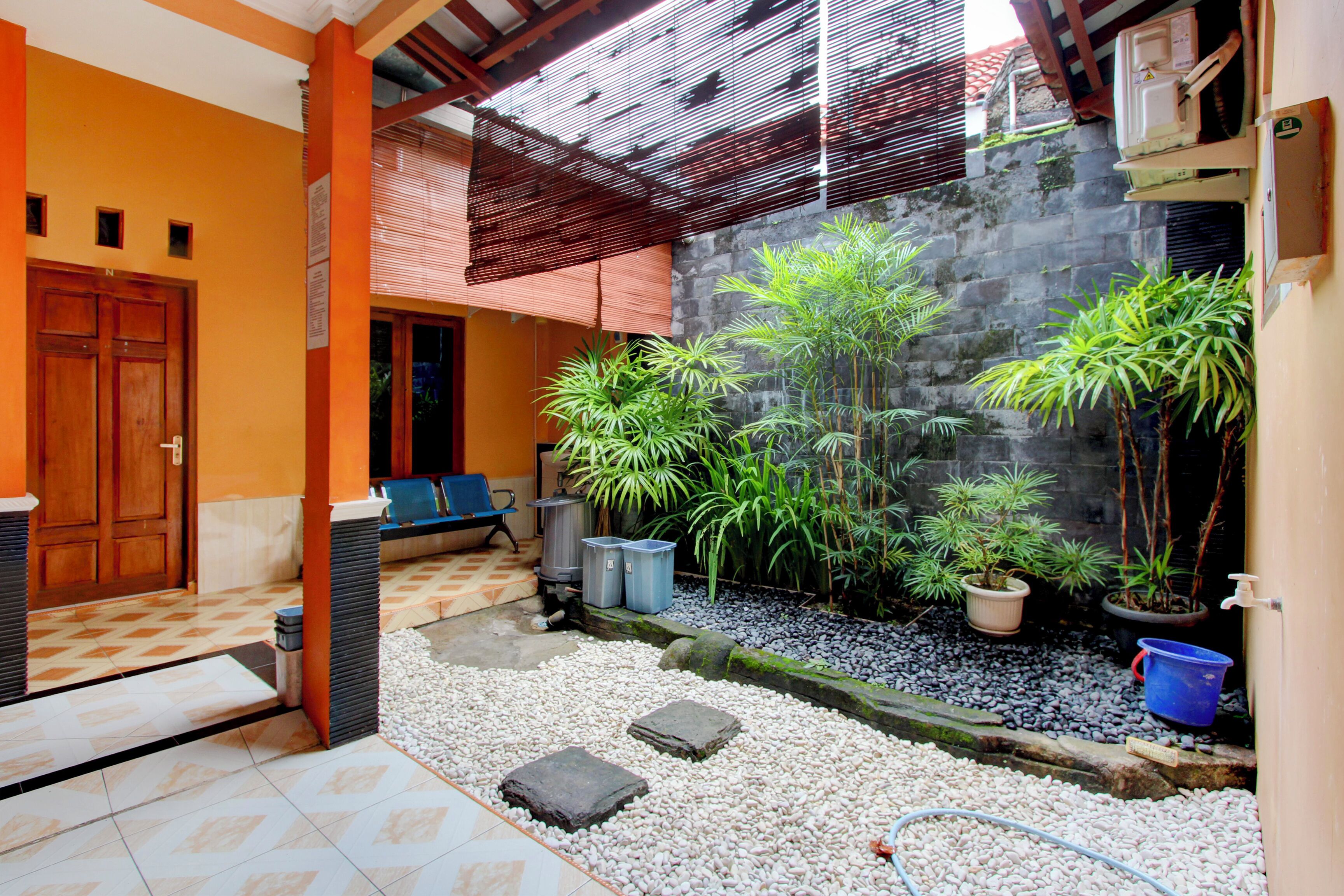 A courtyard with a wooden door, a bench, potted plants, and a water feature.