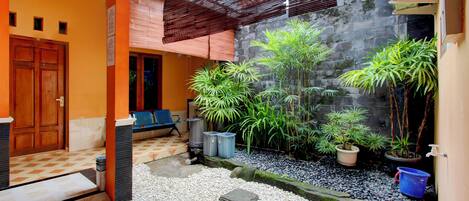 A courtyard with a wooden door, a bench, potted plants, and a water feature.