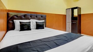 A neatly made bed with a headboard, a bedside table, and a wall-mounted fan. - Hotel O near Ahmad Dahlan University formerly Endrayanti Inn (Yogyakarta)
