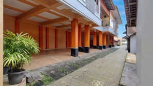 A covered walkway with columns, potted plants, and a tiled path. - Hotel O near Ahmad Dahlan University formerly Endrayanti Inn (Yogyakarta)