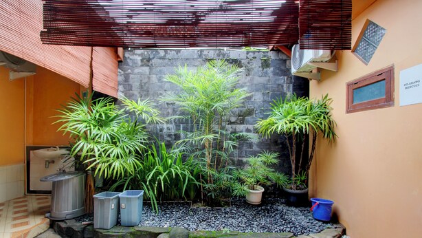 A courtyard with potted plants, a stone wall, and a sign. - Hotel O near Ahmad Dahlan University formerly Endrayanti Inn (Yogyakarta)