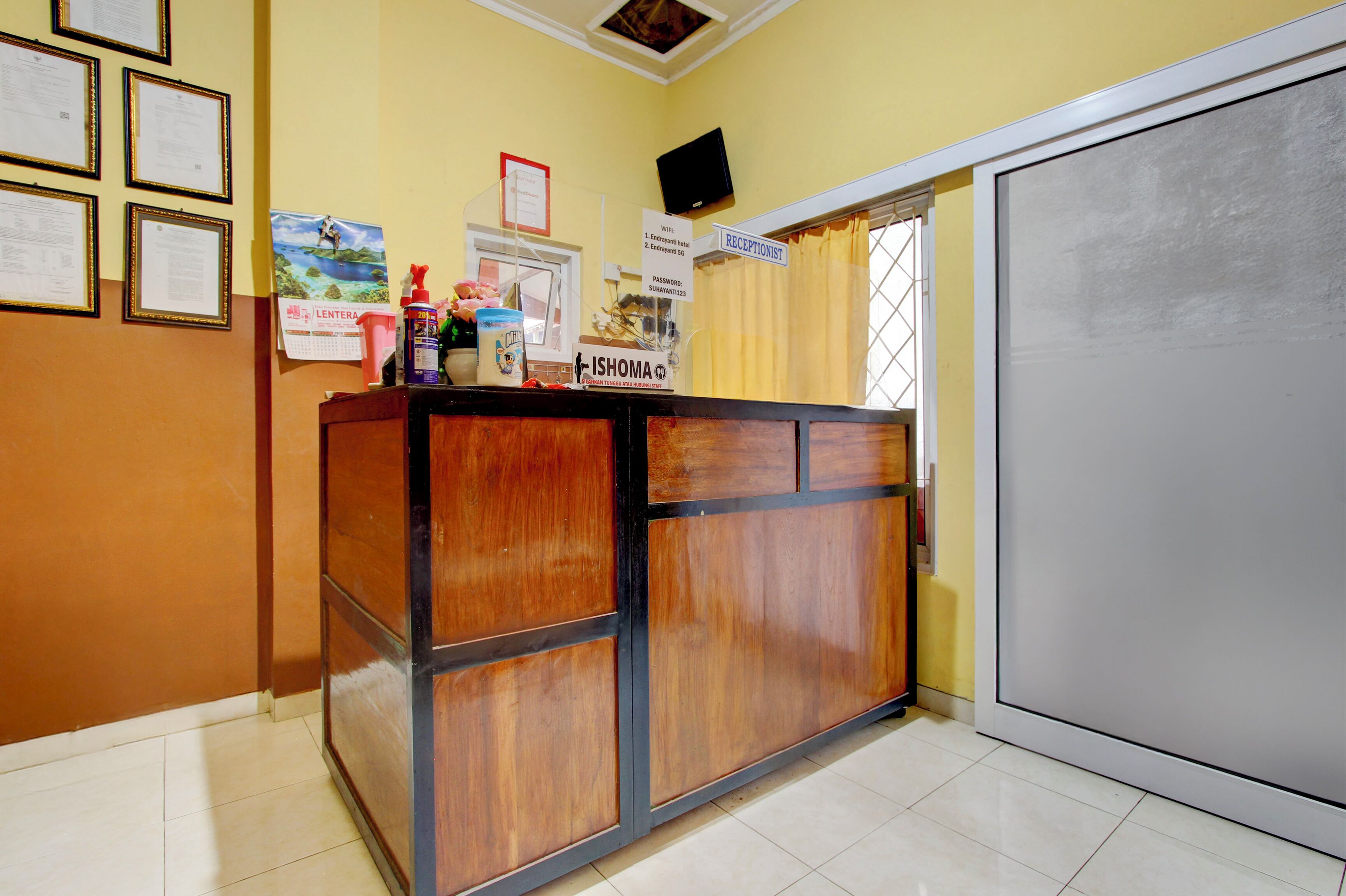 A reception desk with framed certificates, a calendar, and a sign for the receptionist.