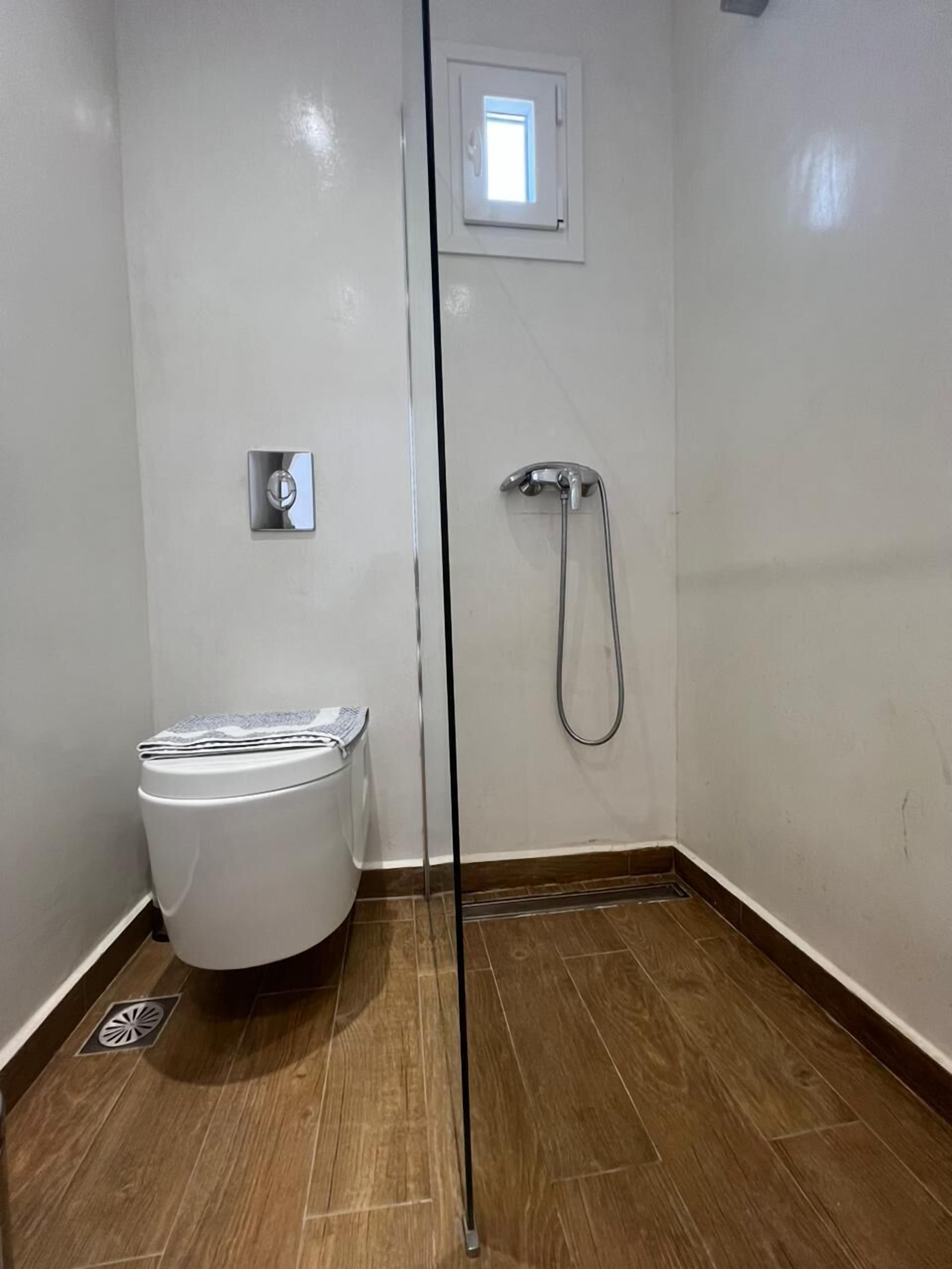 Un baño pequeño y limpio con inodoro, ducha y ventana.