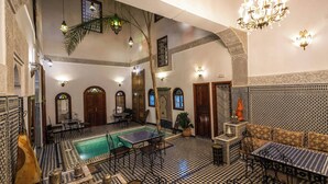 An indoor pool area with tiled flooring, a pool table, and seating arrangements. - Le Cèdre d'Argent (Fes)