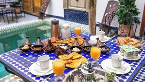 A dining table with a blue and white checkered tablecloth, various dishes, and a glass of orange juice. - Le Cèdre d'Argent (Fes)