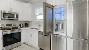 Una cocina moderna con electrodomésticos de acero inoxidable, armarios blancos y lavavajillas integrado.