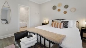 Un dormitorio con una cama grande, una mesita de noche, un espejo y una silla con toallas.