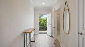 A hallway with a wooden bench, a mirror, and a door leading to a balcony. - Remarkable Superdome Group Home w/Heated Pool, Parking, Patio, 8 Beds & 5 Baths (New Orleans)