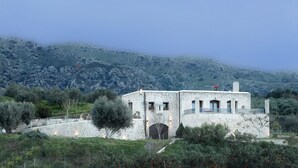 A stone building with a balcony, surrounded by greenery and mountains. - Heliopetra Lux Villa with private Pool (Chania)