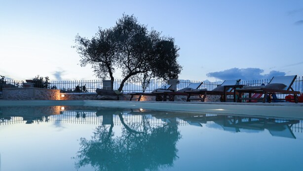 A pool with clear reflections, a tree, and a fence. - Heliopetra Lux Villa with private Pool (Chania)