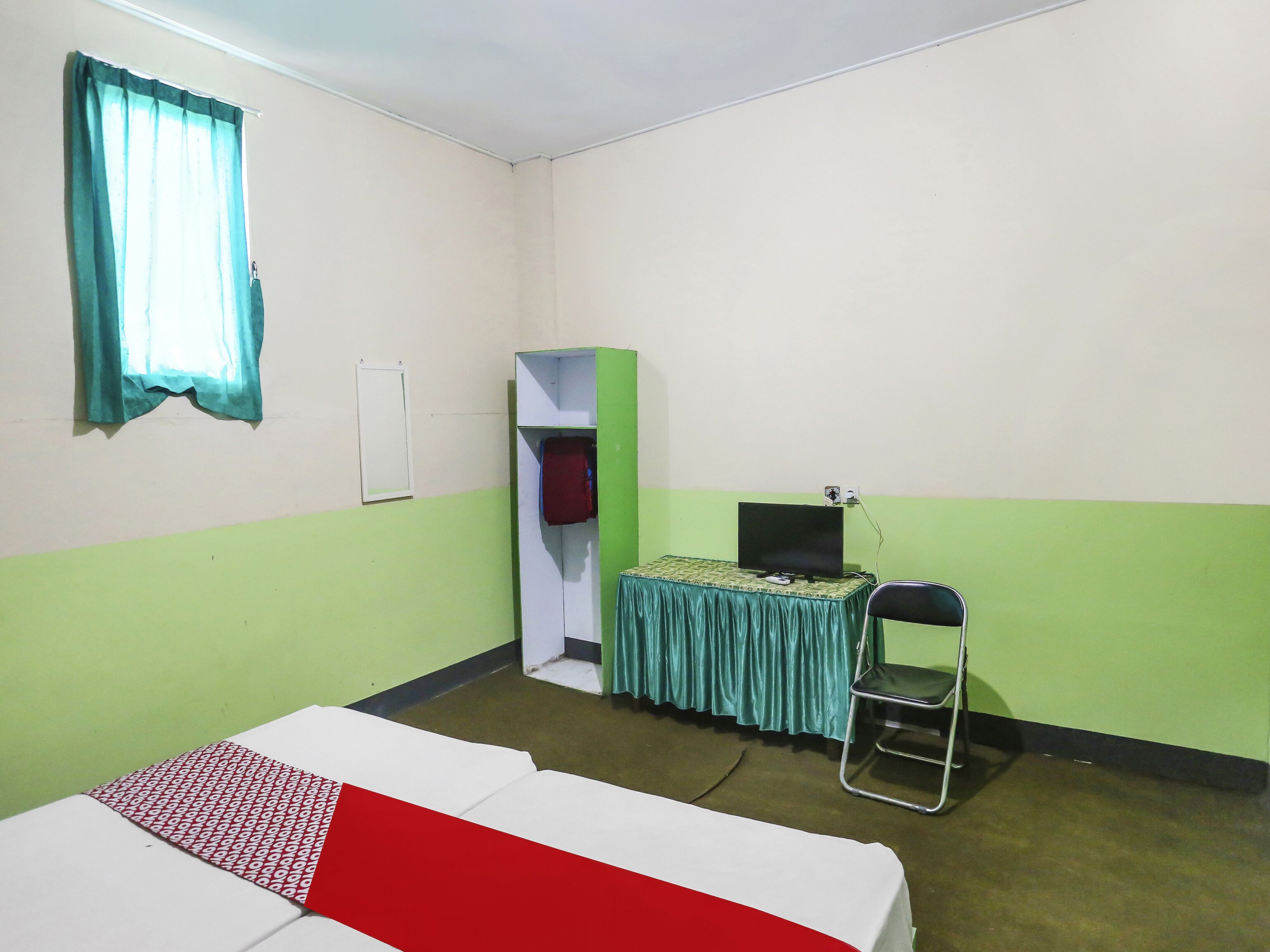 Een kamer met een bed, een bureau met computer, een stoel, een kast en een raam met gordijnen.