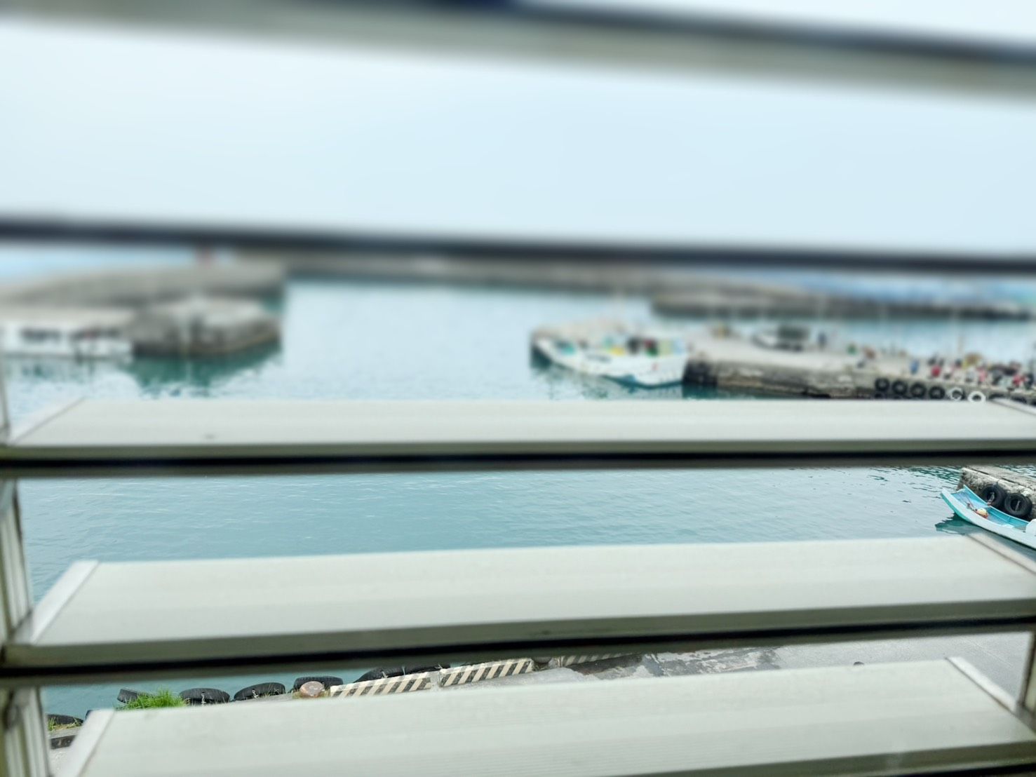 A view through a window of a waterfront area with boats and a pier.