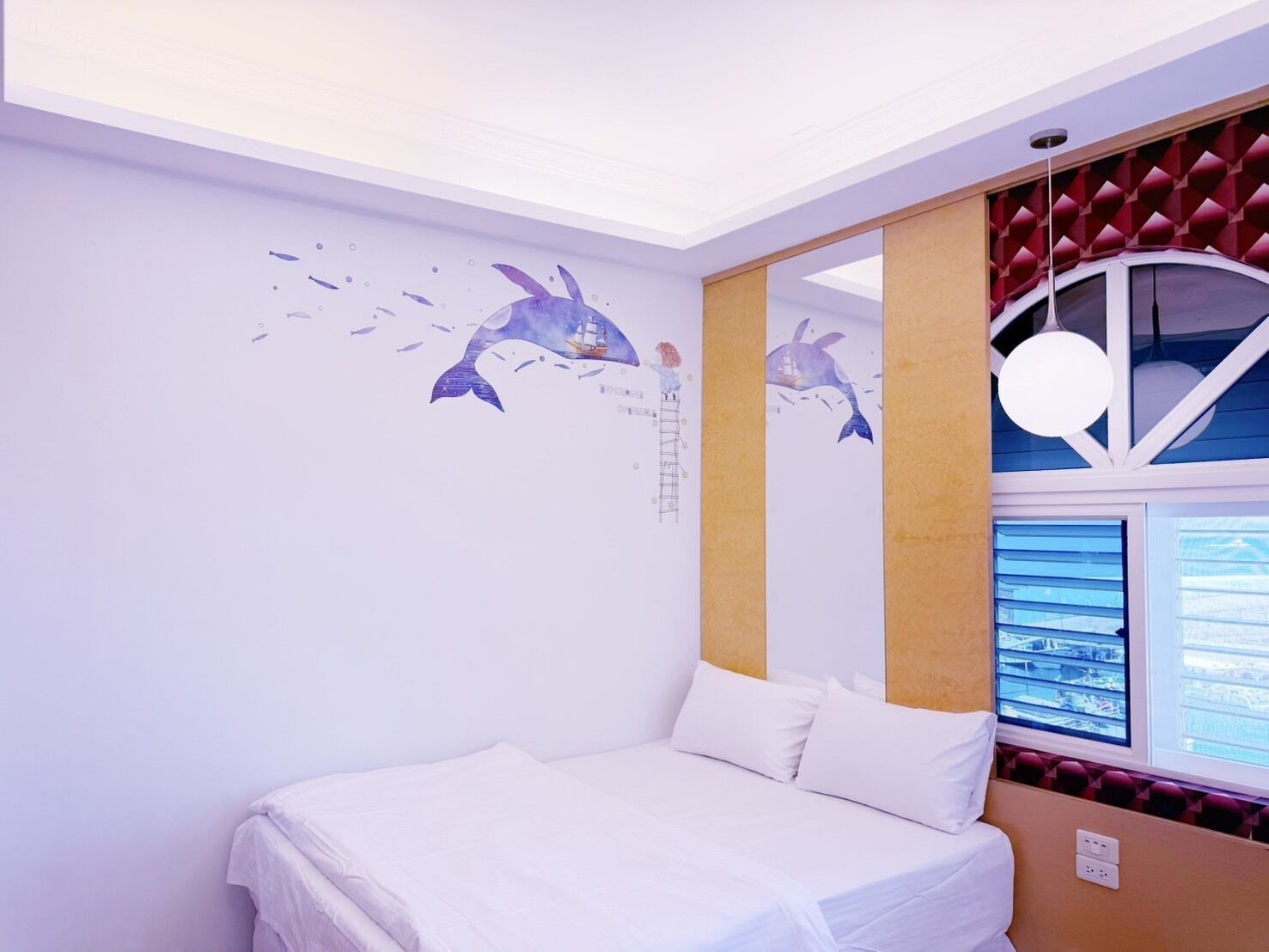 A bedroom with a bed, a window, and a wall mural.