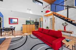 A modern living space with a red sofa, a dining area, and a kitchen.