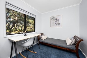A room with a desk, a rocking chair, a globe, and a framed artwork.