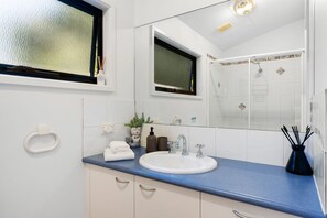 Un baño moderno con un lavamanos blanco, encimera azul y un espejo grande.