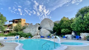 A pool area with two pools, lounge chairs, and large rocks. - AQUA GREEN HOUSE (Porto Rotondo)
