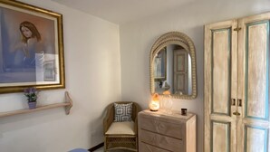 A bedroom with a bed, a dresser, a chair, a mirror, and a door. - AQUA GREEN HOUSE (Porto Rotondo)