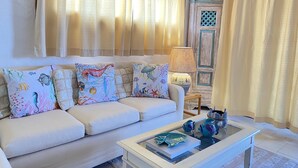 A living room with a white sofa, colorful cushions, a glass coffee table, and a lamp. - AQUA GREEN HOUSE (Porto Rotondo)