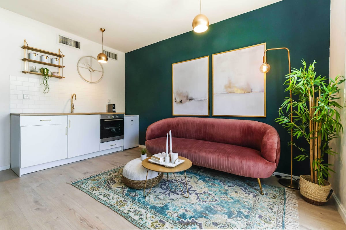 Une cuisine moderne avec des meubles blancs, un canapé rouge et un tapis à motifs.