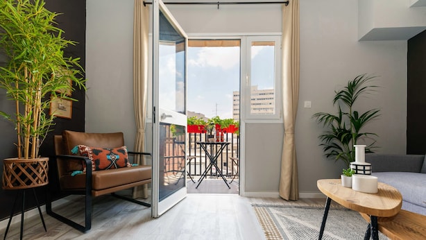 Un salon moderne avec un canapé, une table basse en bois et une porte-fenêtre coulissante donnant sur une terrasse extérieure.