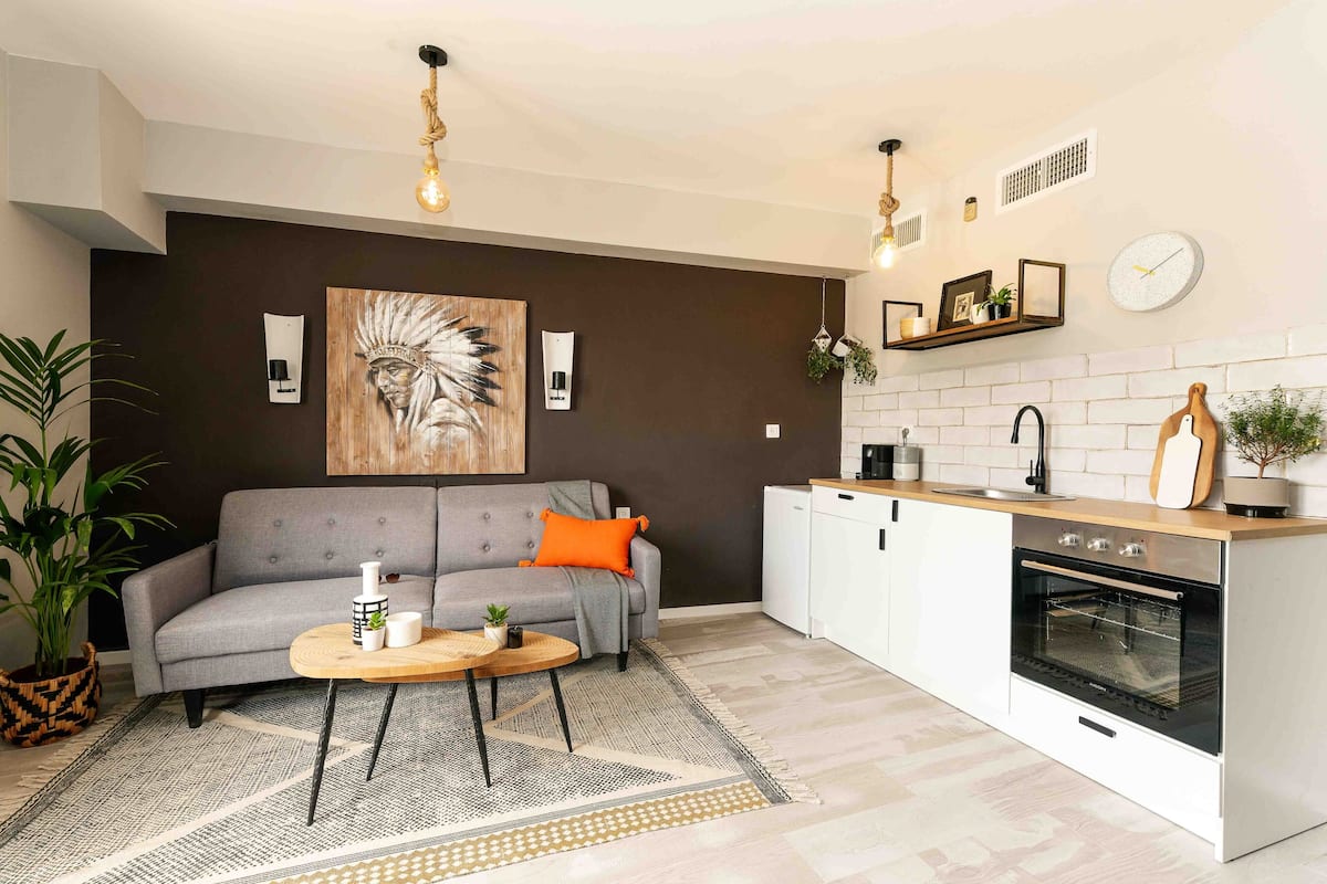 Un salon moderne avec un canapé gris, une table basse ronde et un grand tableau accroché au mur.