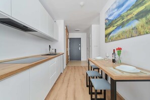 Een koelkast, een magnetron, een kookplaat, kookgerei, borden en bestek