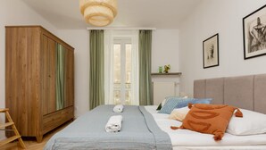 A bedroom with a bed, a wardrobe, a radiator, and a window with curtains. - Comfortable Apartment in Downtown | A place to work (Warszawa)