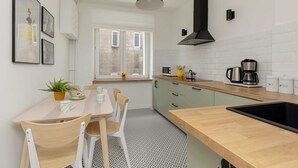 A modern kitchen with a wooden countertop, a black range hood, and a window with a view of the outside. - Comfortable Apartment in Downtown | A place to work (Warszawa)