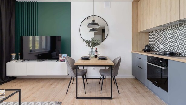 Una cocina moderna con comedor, televisor y un espejo grande.