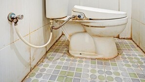 A bathroom with a toilet, a toilet paper holder, and a patterned floor.